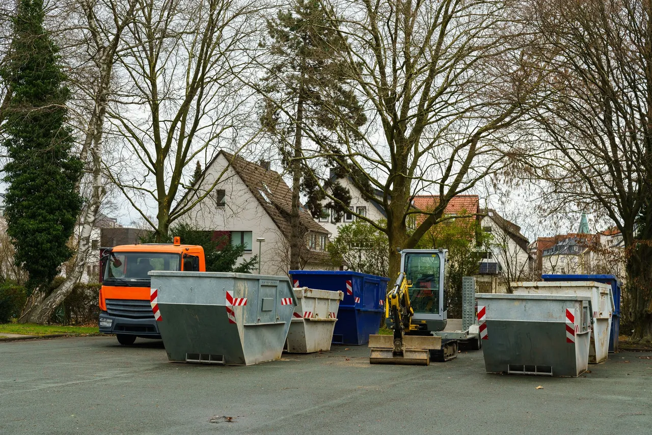 A lot of dumpsters and trucks are parked in a parking lot.
