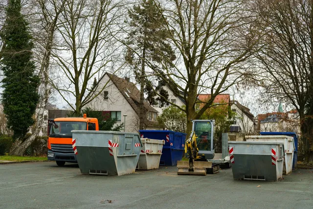 A lot of dumpsters and trucks are parked in a parking lot.